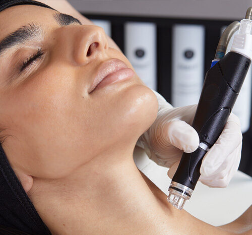 Frau lässt sich mit Hydrafacial im Gesicht in einem Kosmetikstudio in behandeln.